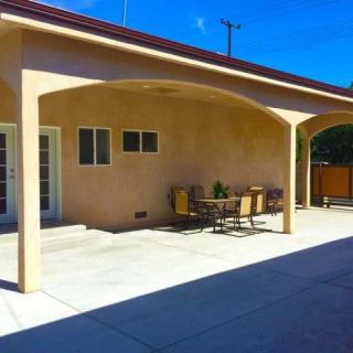 A sunny outdoor patio area with a covered section and dining furniture.