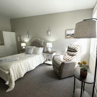 A cozy bedroom with a comfortable bed, plush chair, and elegant decor.
