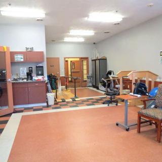 A multi-purpose room with a kitchenette, seating area, and office equipment.