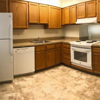 A modern kitchen with wooden cabinets and essential appliances.
