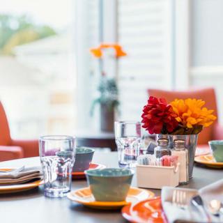 A beautifully arranged dining table with colorful flowers and dishware.