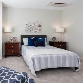 A modern bedroom with a neatly made bed, two side tables, and stylish decor.