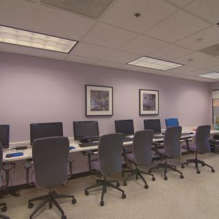 A computer lab with several workstations equipped with computers and office chairs.