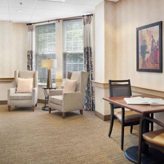 A cozy living room with comfortable chairs and a small table near large windows.