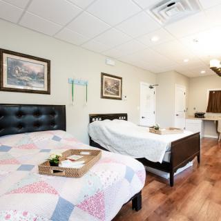 A well-lit bedroom featuring two beds, wooden flooring, and decorative wall art.