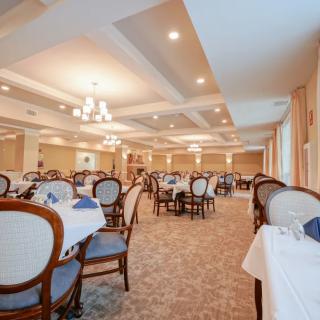 Elegant dining room with neatly arranged tables and chairs, highlighted by soft lighting.