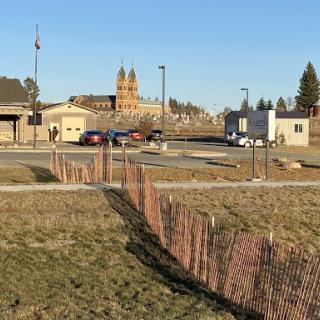 A view of a historic building in the background, along with modern structures and a fence in the foreground.