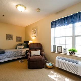 A cozy bedroom with a bed, armchair, and large window.