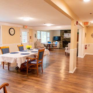 A cozy dining area in a residential setting, featuring wooden floors and well-arranged tables.