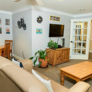 A cozy living room with a sofa, coffee table, TV, and dining area.