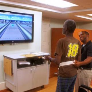 Two people enjoy a game of virtual bowling using a Wii console in an indoor setting.
