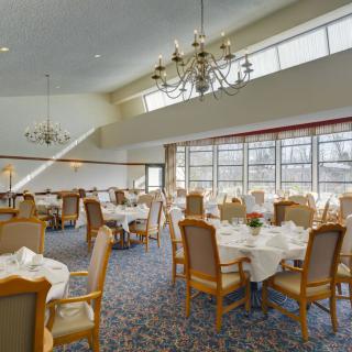 An elegant dining room with neatly arranged tables and chandeliers.