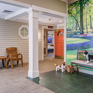An indoor space featuring a bench with artificial pet figures and a vibrant mural of a forest scene on the wall.