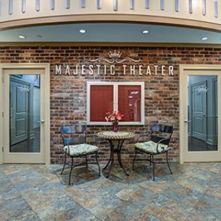 An interior view of the Majestic Theater entrance, featuring a brick wall and a seating area with a small table and two chairs.