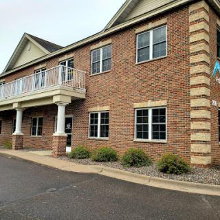 A two-story brick building featuring multiple windows and a covered balcony.
