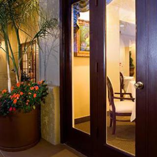 A cozy interior space with elegant decor, featuring a glass door and a large potted plant.