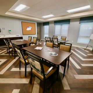 A modern conference room with tables and chairs arranged facing a projector screen.