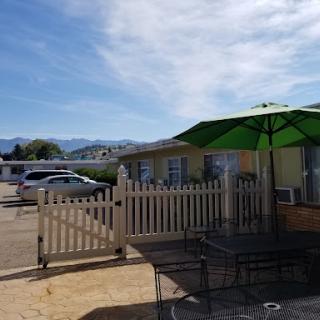 A cozy outdoor seating area with a green umbrella and a view of the mountains.