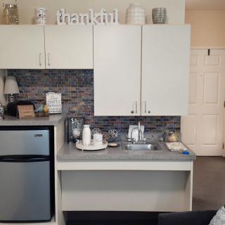A modern kitchenette with a mini fridge, cabinets, and decorative elements on the countertop.