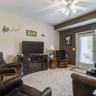A cozy living room with comfortable seating and a large TV, featuring a ceiling fan and stylish decor.
