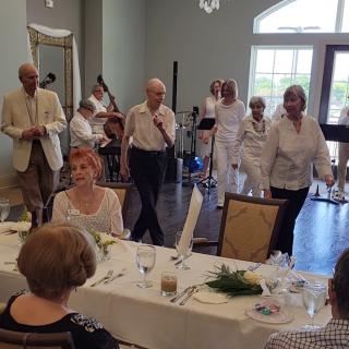 A group of people enjoying a gathering with music and dining indoors.