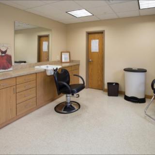 A minimalist hair salon interior with a single barber chair and a large mirror.