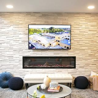 A modern living room featuring a sleek fireplace and a wall-mounted television above a stone accent wall.