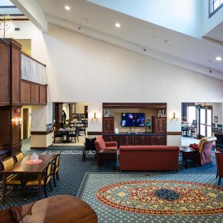 A spacious and well-furnished lounge area featuring comfortable seating, a television, and decorative carpeting.
