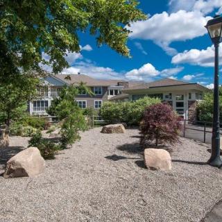 A scenic view of a landscaped garden with rocks and trees in front of a large building under a partly cloudy sky.