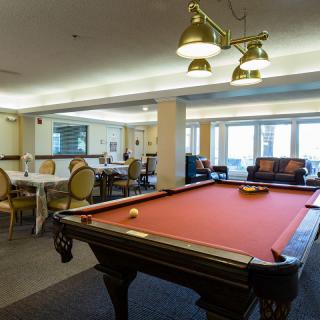 A cozy recreation room featuring a pool table with red felt and elegant lighting.