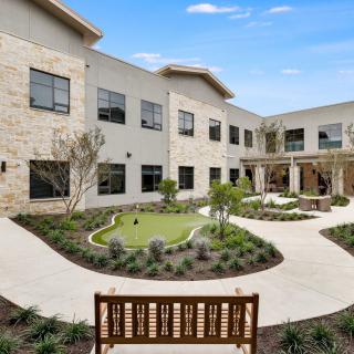A modern building with a landscaped courtyard, featuring benches and pathways.