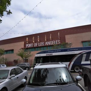 View of the Port of Los Angeles with parked vehicles and a city bus.