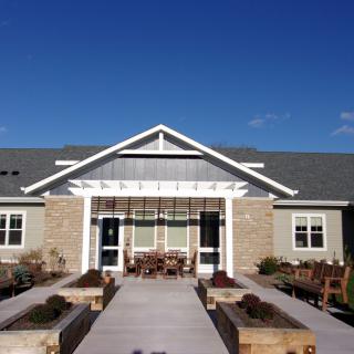 A modern residential building with a landscaped entrance and clear blue sky.