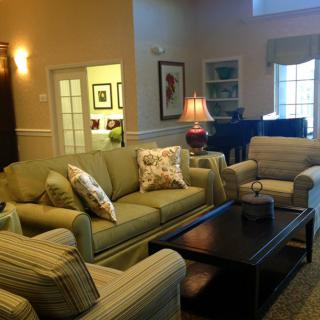 A cozy living room with comfortable seating, a piano, and warm lighting.