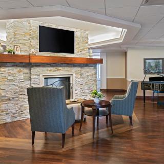 A modern living room with a stone fireplace, two armchairs, a small coffee table, and a TV mounted above the mantle.