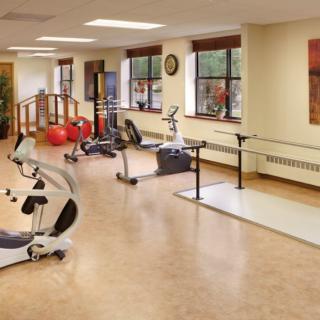 A spacious gym area with various fitness and rehabilitation equipment.