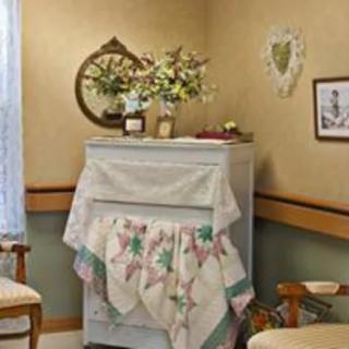 A cozy, vintage-style room featuring a cabinet draped with a floral tablecloth and adorned with decorative items.