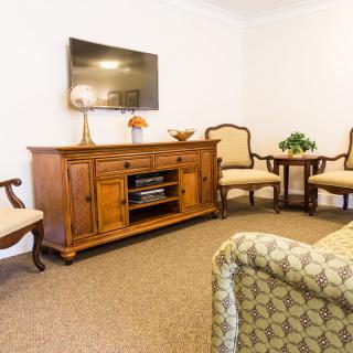 A cozy living room with classic wooden furniture and a wall-mounted television.