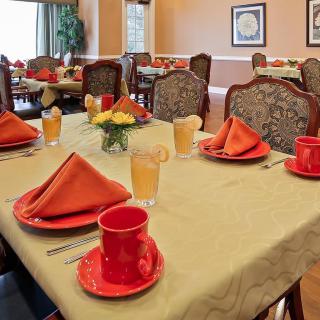 A well-set dining table with red dishes and napkins in an elegant dining room.