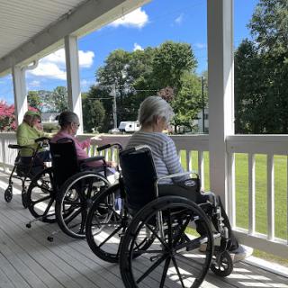 Elderly individuals enjoying a sunny day outside the care facility.