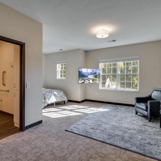 Spacious bedroom with a bed, armchair, and wall-mounted TV.