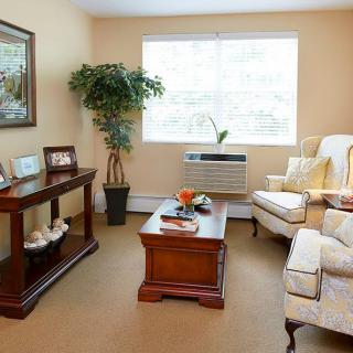 A cozy living room with comfortable seating, a wooden coffee table, and a large window letting in natural light.