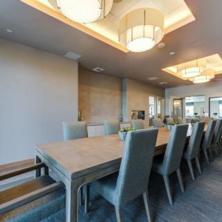 A modern dining room with a large table and elegant chairs, featuring stylish ceiling lights.