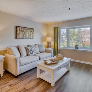 A cozy and well-decorated living room with a comfortable sofa, coffee table, and large window.