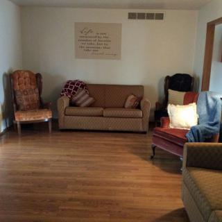 A cozy living room with a sofa, armchairs, and wooden flooring.