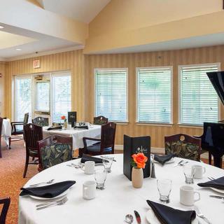 An elegant dining room with neatly arranged round tables and black napkins.