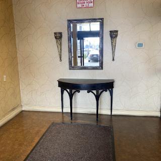 A cozy entrance area featuring a sleek black table and a mirror, adorned with wall sconces.