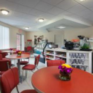 A cozy caf interior featuring round tables and bright red chairs, adorned with colorful floral centerpieces.