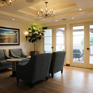 A cozy living room with elegant chandeliers, comfortable seating, and large glass doors leading to a balcony.