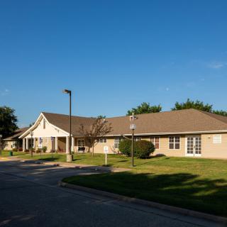 A suburban residential building with a neatly maintained lawn under a clear blue sky.